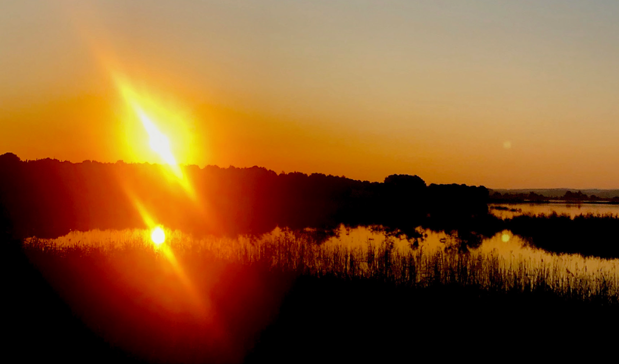 Amanecer en La Estanca de Alcañiz. El sol a la izquierda y la luna a la derecha de la imagen se reflejan en el agua pareciendo que tenemos soles y lunas en nuestra galaxia. Al margen de la imaginación, nuestro planeta depende totalmente del sol y se ve afectado por la luna, así como por muchos fenómenos atmosféricos que van evolucionando naturalmente. J.E.